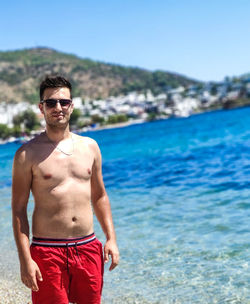 Portrait of young man standing against sea