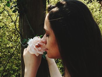 Close-up of woman smelling flower in forest