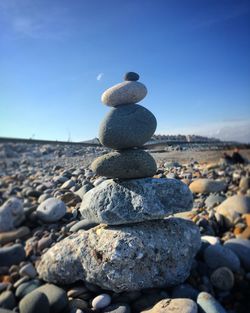 Stacked stones at beach against sky