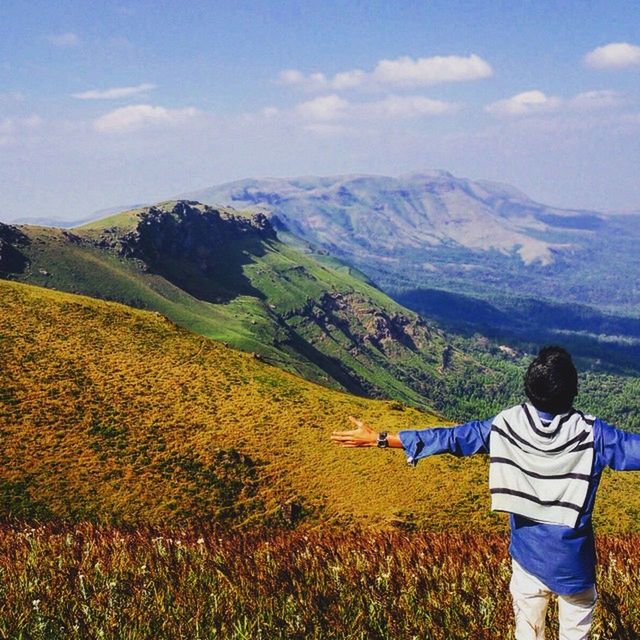 mountain, landscape, leisure activity, beauty in nature, lifestyles, mountain range, tranquil scene, sky, tranquility, scenics, nature, casual clothing, grass, field, rear view, non-urban scene, standing, cloud - sky