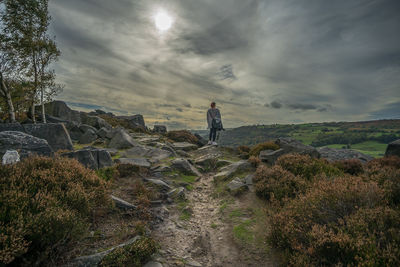 Man standing on rock against sky