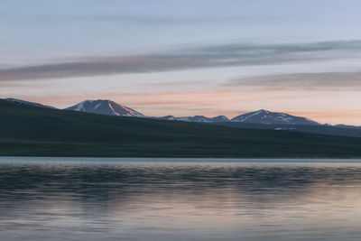Scenic view of lake by mountains against sky during sunset