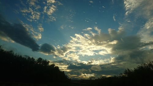 Silhouette of trees against cloudy sky