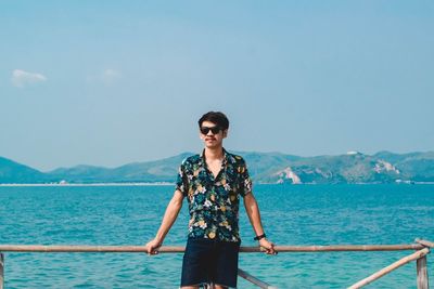 Portrait of young man standing against sea and blue sky