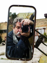 Reflection of man photographing in mirror