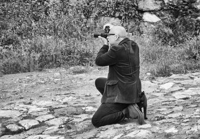 Man photographing with camera on land against plants