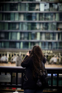 Rear view of woman sitting against buildings