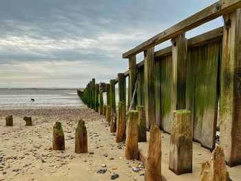 Wooden posts on beach against sky