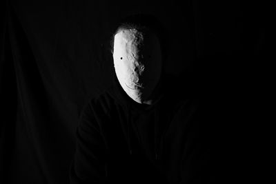 Portrait of man against black background wearing mask