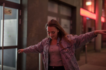Woman with arms outstretched walking in city