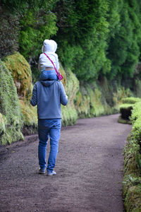 Rear view of woman walking on road amidst trees