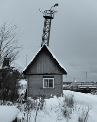 House on snow covered field against sky