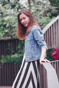 Beautiful young woman standing against railing