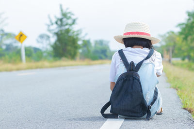 Rear view of woman with backpack on road