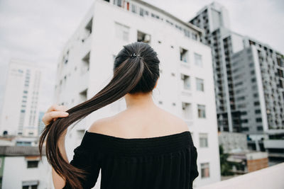 Rear view of woman standing against buildings in city