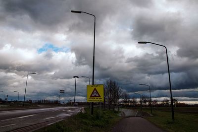 Road sign against cloudy sky