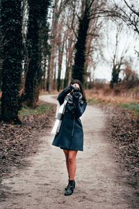 Full length of woman photographing in forest