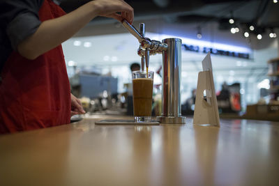 Midsection of female worker preparing coffee in cafe