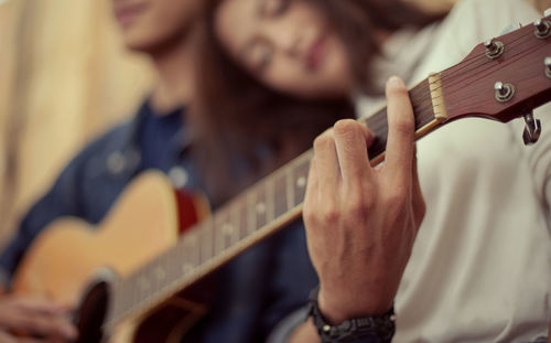 Midsection of man playing guitar