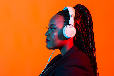 Portrait of young woman against orange wall