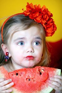 A 3 year old girl eats a watermelon.