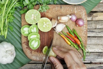 Cropped image of person holding fruits on cutting board