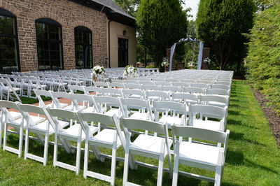 Outdoor wedding set up with white chairs in a garden.