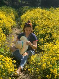 Woman standing by yellow flowering plants