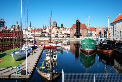 Boats moored at harbor against buildings in city