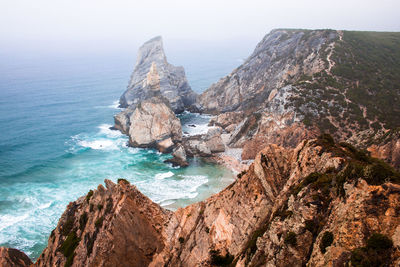 Scenic view of sea against rocky mountains