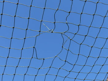 Low angle view of tall fence against blue sky