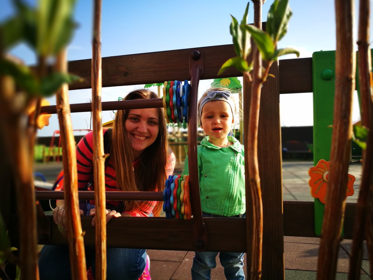 childhood, real people, playground, girls, togetherness, leisure activity, casual clothing, elementary age, lifestyles, wood - material, front view, day, boys, sitting, happiness, outdoors, bonding, looking at camera, two people, playing, portrait, smiling, young women, young adult, nature