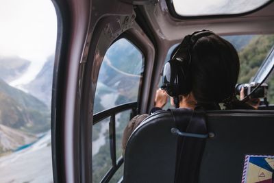 Rear view of woman sitting in helicopter cockpit