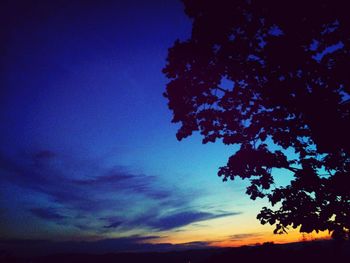Low angle view of silhouette tree against blue sky