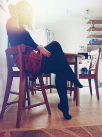 Side view of woman sitting on chair at home