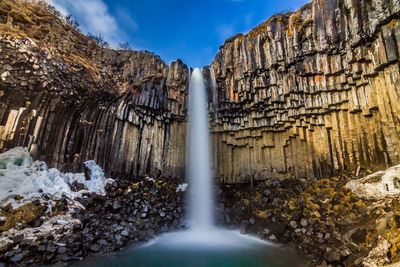 Scenic view of waterfall falling from mountain