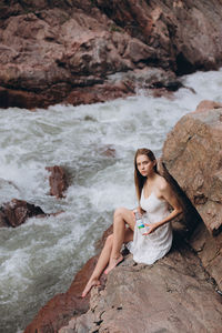 Portrait of young woman sitting on rock