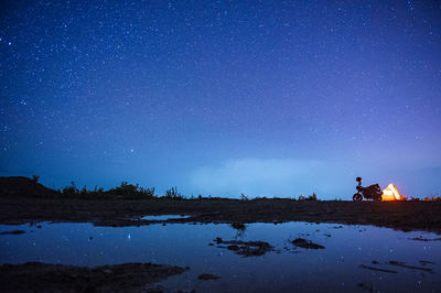 People on shore against blue sky at night