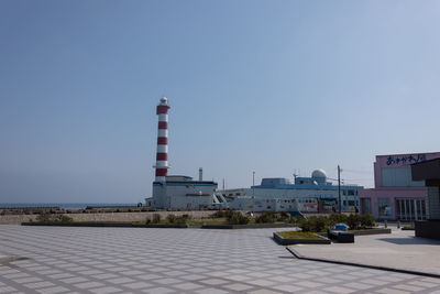 Lighthouse by sea against clear sky