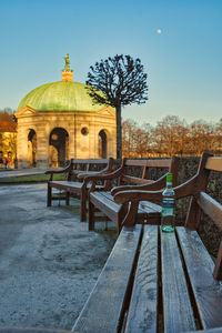 Empty benches in park against clear sky