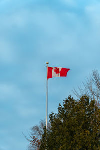 Low angle view of red flag on pole against sky