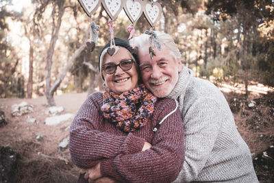 Portrait of smiling senior couple embracing in forest 