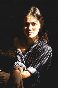 Close-up portrait of young woman against black background