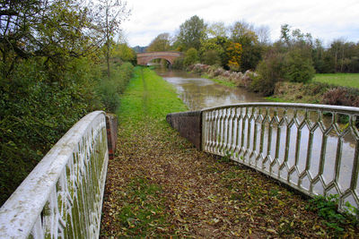 Footbridge over stream against sky