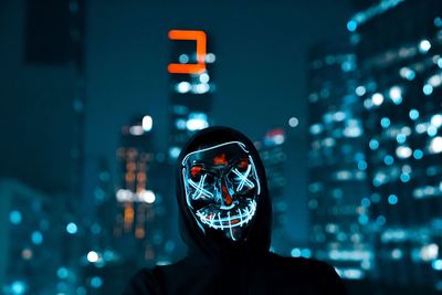 Man wearing illuminated mask in city at night