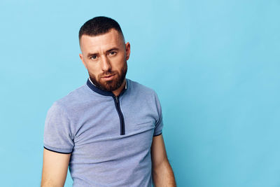 Young man standing against blue background