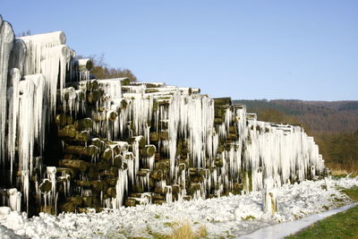 Panoramic shot of icicles on field against clear sky during winter