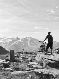 Rear view of man standing on mountain against sky