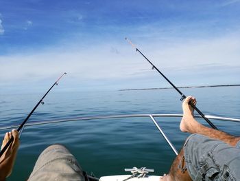 Low angle view of men at boat on sea against sky