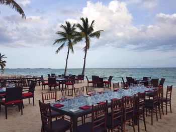 Chairs and tables at beach against sky